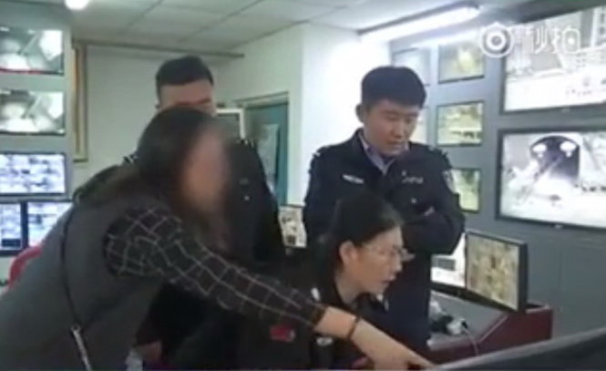 Người phụ nữ chỉ cho cảnh sát xem hình ảnh kẻ đánh cô trong camera - Ảnh chụp từ clip