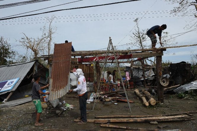 Một gia đình sửa lại nhà tại tỉnh Isabela, Philippines sau khi bão Haima ập đến - Ảnh: AFP