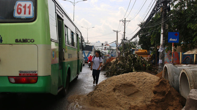 Đất cát, vật liệu của đơn vị thi công đổ tràn ra đường Lê Văn Việt khiến người đi bộ phải đi ra lòng đường - Ảnh: LÊ PHAN