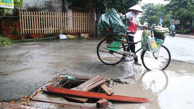 Một hố ga trên đường Đình Phong Phú hư hỏng chưa được sửa chữa, người dân phải dùng ván che chắn tạm - Ảnh: LÊ PHAN