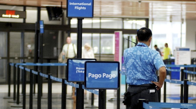 Một nhân viên hãng hàng không đứng cạnh khu vực làm thủ tục đi Pago Pago của hãng Hawaiian Airlines - Ảnh: AP