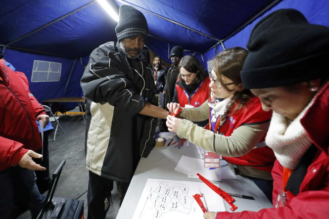 Người xin tị nạn ở Calais được “đánh dấu” bằng vòng màu đeo tay để đi về các trung tâm tiếp nhận -Ảnh: Reuters