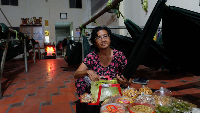 Bà Phạm Thị Hoa sắp xếp thúng bánh bán cho người buôn bán trong chợ đầu mối Thủ Đức trước khi rời quán võng đêm - Ảnh: VŨ THỦY