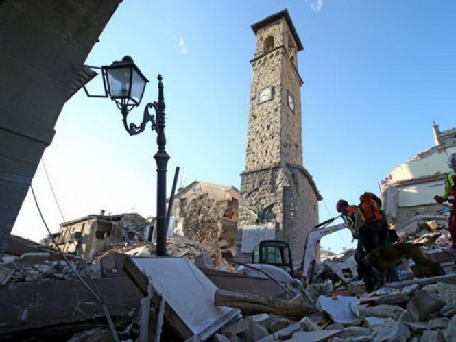 Nhân viên cứu hộ đi qua đống đổ nát sau trận động đất tại Amatrice, trung Ý Ảnh: Reuters