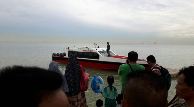 Người dân đứng xem tàu cứu hộ đi cứu nạn nhân lật tàu - Ảnh: thejakartapost.com