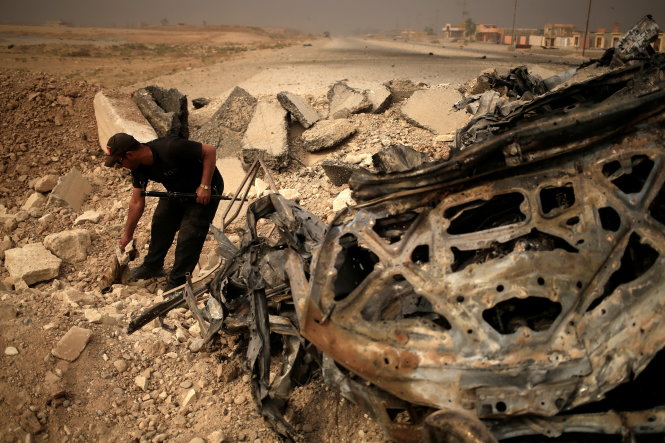 Thành viên lực lượng đặc nhiệm Iraq nhặt phần tay còn lại của một tay súng IS đánh bom tự sát ở phía đông Mosul, ngày 1-11 - Ảnh: Reuters