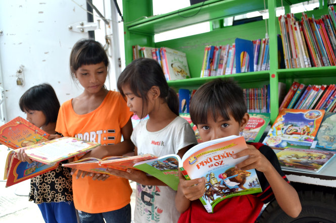 Bốn bé gái dân tộc Chăm đang học Trường tiểu học số 2 thị trấn Vân Canh không rời các cuốn truyện tranh của “Chiếc xe tri thức” - Ảnh: DUY THANH