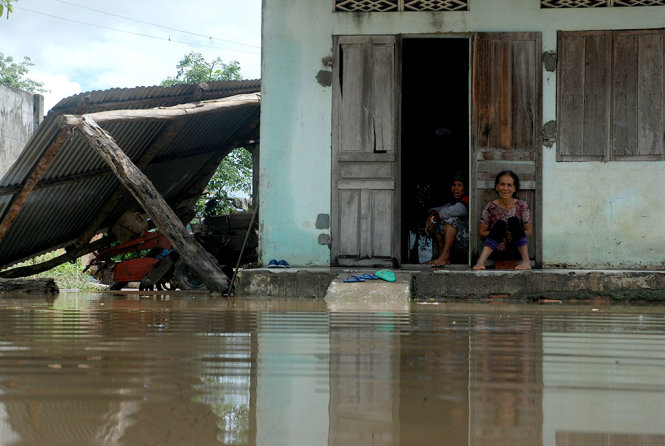 Một người dân ở buôn Krông, huyện Krông Ana ngồi đợi nước lũ rút, bên cạnh là gian nhà che máy móc đã bị đổ sập do lũ - Ảnh: B.D
