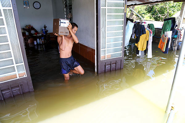 Nước ngập vào trong nhà khoảng 30cm, Trần Mạnh Linh (29 tuổi, thôn Hà Lâm) di chuyển một số vật dụng ra khỏi nhà vì sợ nước tiếp tục dâng cao - Ảnh: M.V