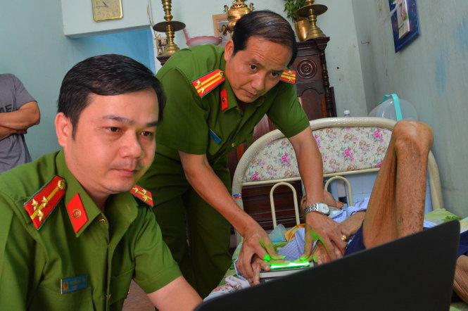 Trung tá Nguyễn Văn Trường (phải) cùng đồng nghiệp đến nhà làm thẻ căn cước cho ông Lương Sỹ
(88 tuổi, Q.12) bị liệt - Ảnh: LĨNH HỒNG