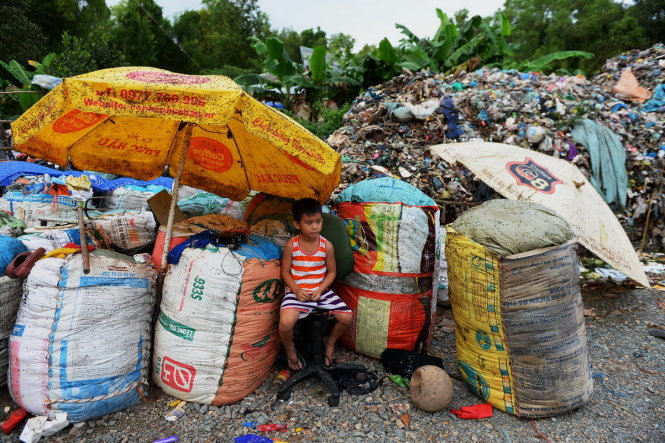Bé Lê Minh Nhật ngồi chờ ba mẹ nhăt rác xung quanh là ruồi và mùi hôi nồng nặc