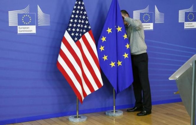 Ảnh tư liệu cho thấy một nhân viên đang sửa lại cờ EU và cờ Mỹ khi chuẩn bị bắt đầu vòng đàm phán thứ 2 về TTIP tại Brussels năm 2013 - Ảnh: Reuters