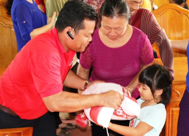 Ông Phạm Văn Sen, đại diện nhà tài trợ trao quà cho một em bé ở xã Cẩm Thạch (Cẩm Xuyên, Hà Tĩnh) thay bố mẹ đi nhận - Ảnh: VĂN ĐỊNH