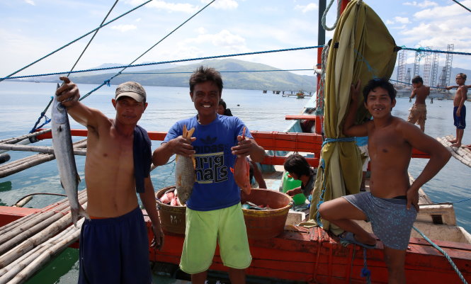 Fishermen, who has just returned from fishing in disputed Scarborough Shoal, hold fish as they pose before the media in Subic, Zambales in the Philippines, November 1