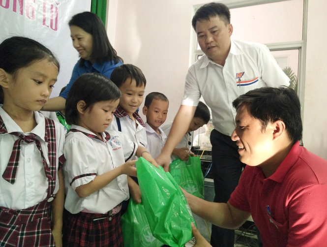 Đại diện báo Tuổi Trẻ và Công ty RICO FEED trao quà cho học sinh khó khăn ở vùng lũ Phước Thắng (huyện Tuy Phước, tỉnh Bình Định) chiều 25-11 - Ảnh: Trường An