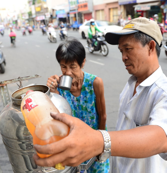 Ông Đỗ Văn Út châm nước cho thùng trà đá miễn phí tại hẻm 96 Phan Đình Phùng (P2, Q.Phú Nhuận, TP.HCM) - Ảnh: D.PHAN