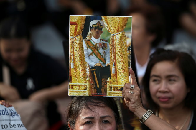 A woman holds up a picture of Thailand's Crown Prince Maha Vajiralongkorn before he arrives at the Grand Palace in Bangkok, Thailand, December 1