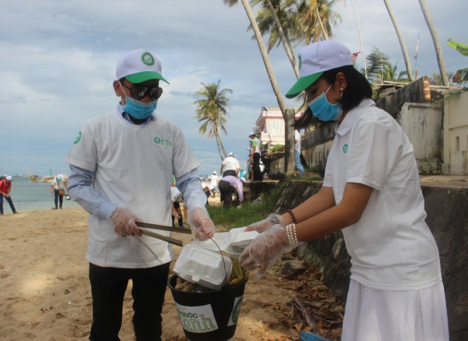 Diễn viên Việt Trinh và Trung Trần cùng du khách nhặt rác trên bãi biển Dinh Cậu sáng 2-12 - Ảnh: Nguyễn Triều