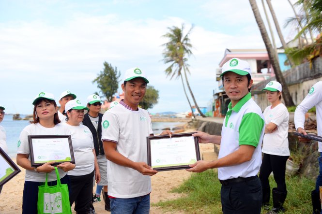Ông Trần Xuân Toàn - Đại diện báo Tuổi Trẻ trao thư cảm ơn của ban tổ chức cho người dân tham gia nhặt rác tại bãi biển Dinh Cậu - Ảnh: Hữu Khoa