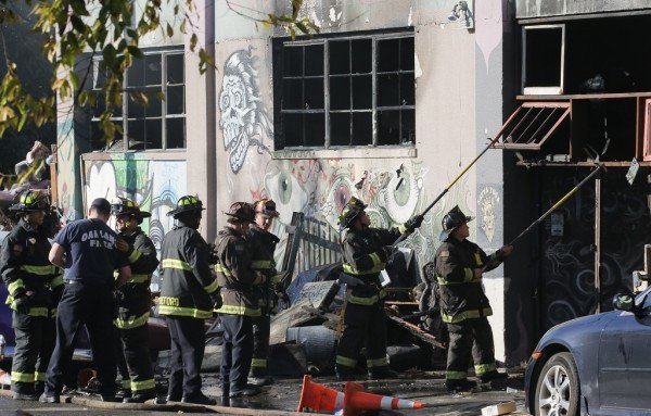 Lính cứu hỏa dọn dẹp các mảnh vỡ và vật dụng bị cháy trong vụ hỏa hoạn ở Oakland - Ảnh: AFP