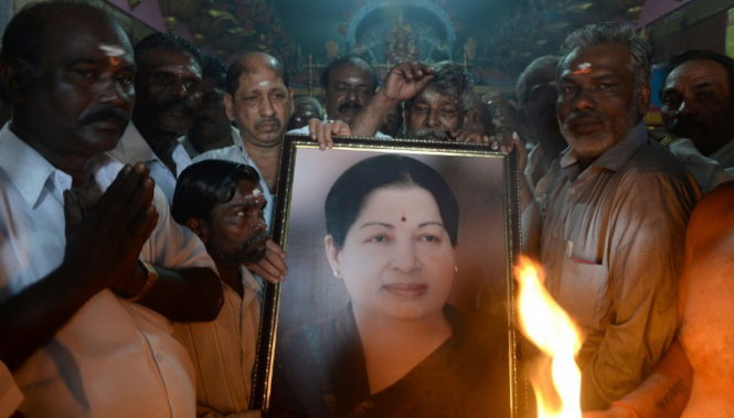 Những người ủng hộ cầm ảnh bà Jayalalithaa Jayaram khi họ cầu nguyện cho bà ở Mumbai hôm 5-12 - Ảnh: AFP
