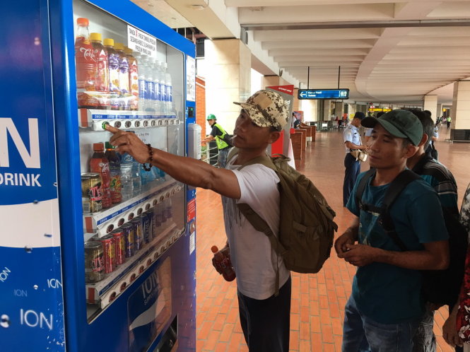 Thử mua nước uống tại máy bán nước tự động ở sân bay Jakarta - Ảnh: Lê Nam