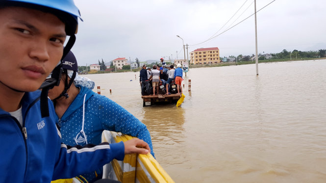 Đến chiều 8-12, nhiều khu vực ở huyện Tuy Phước (tỉnh Bình Định) còn ngập, người dân phải “tăng bo” bằng xe tải để qua các tràn ngập lũ - Ảnh: DUY THANH