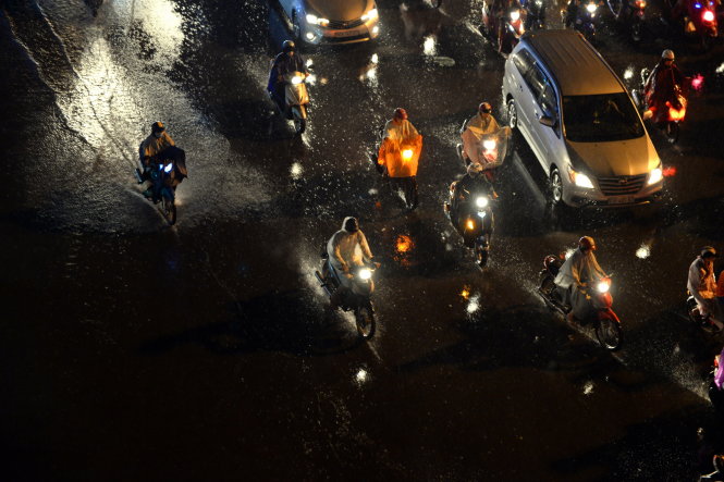 Người dân đội mưa về nhà để tránh kẹt xe - Ảnh: Hữu Khoa