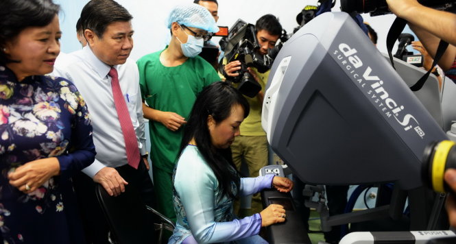 Bộ trưởng Bộ Y tế Nguyễn Thị Kim Tiến đang thử điều khiển robot phẫu thuật tại bệnh viện Bình Dân - Ảnh: Hữu Khoa