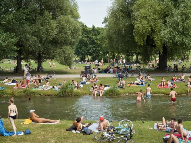 Ảnh chụp từ Đức: Người thư giãn bên hồ vào mùa hè ở Schwabinger Bach (thành phố Munich). Có người khỏa thân hoàn toàn để tắm nắng trên bãi cỏ - Ảnh: SIMON ROBERTS