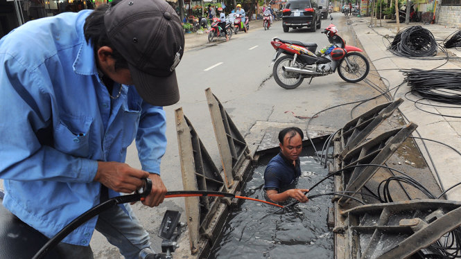 Công nhân đang tiến hành ngầm hoà cáp viên thông trên đường Quốc Hương quận 2 TP.HCM - Ảnh: TỰ TRUNG