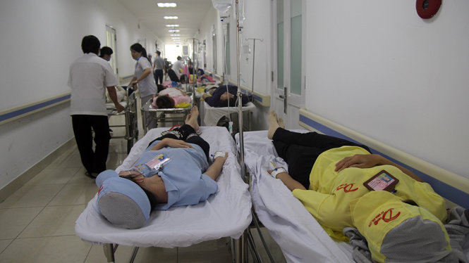 Do số lượng công nhân nhập viện cùng một lúc quá đông nên bệnh viện phải sắp xếp cho bệnh nhân nằm tạm trên băng ca, đặt ngoài hành lang để truyền nước - Ảnh: MẬU TRƯỜNG