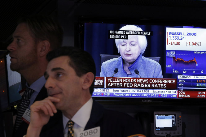 Một nhà đầu tư làm việc tại sàn giao dịch chứng khoán New York, trong lúc tivi phát bản tin chủ tịch FED Janet Yellen họp báo công bố tăng lãi suất - Ảnh: Reuters