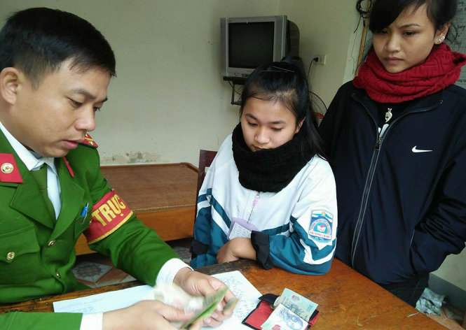 Hai em học sinh huyên Hương Khê bàn giao lại số tiền nhặt được cho cơ quan công an để tìm người trả lại - Ảnh: THẮNG DINH
