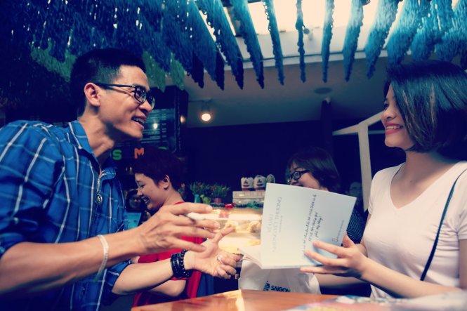 Nguyễn Phong Việt vui vẻ kí tặng cho độc giả yêu thơ anh tại buổi giao lưu chiều 17-12 Ảnh Gia Tiến