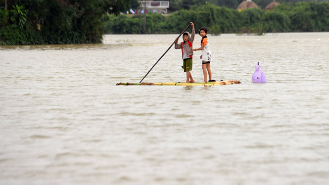 Trẻ em Thôn Diêu Trì, Thị trấn Diêu Trì, huyện Tuy Phước, tỉnh Bình Định) đi lại bằng bè chuối nguy hiểm trong dòng nước chảy mạnh - Ảnh: HỮU KHOA