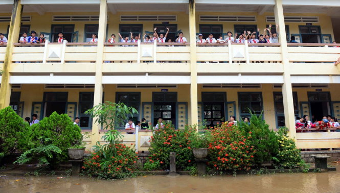 Mặc dù sân trường vẫn còn ngập nước nhưng các em đến lớp rất đông trong ngày học đầu tiên khi lũ rút - Ảnh: HỮU KHOA