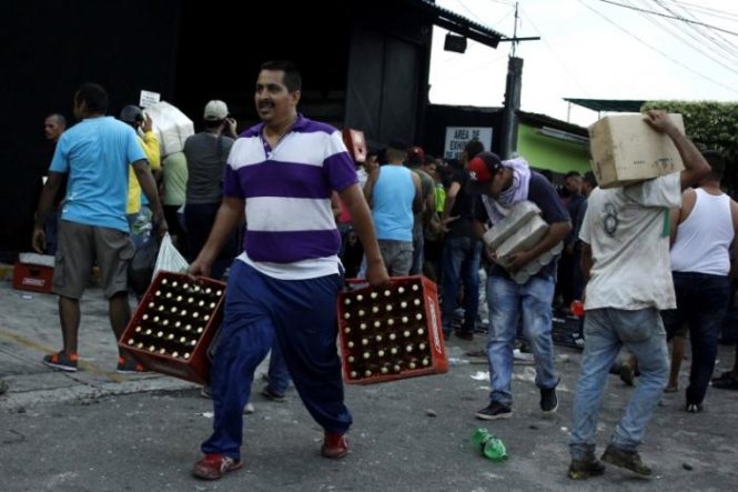 Người dân xách những món đồ lấy được từ một khu bán sỉ thực phẩm sau khi nó bị đột nhập tại La Fria, Venezuela ngày 17-12-2016 - Ảnh: Reuters
