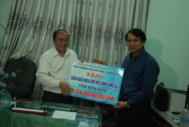 Thứ trưởng Phạm Mạnh Hùng trao khoản hỗ trợ ban đầu của Bộ GD-ĐT  giúp H. Phù Cát (Bình Định) mua sách vở cho học sinh - Ảnh: B.D