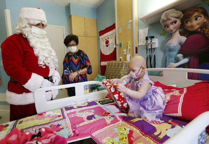 “Ông già Noel” phát quà cho bé gái Luciana Trijjano, 3 tuổi tại bệnh viện nhi đồng ở Miami (Mỹ) - Ảnh: AP