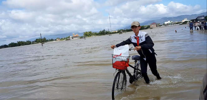 Em Nguyễn Văn Đạt, học sinh lớp 9 Trường Trường THCS Phước Hòa (huyện Tuy Phước, tỉnh Bình Định), lội lũ về lại nơi ở nhờ sau khi nhận học bổng. Nhà của Đạt đã bị lũ cuốn trôi hoàn toàn – Ảnh: DUY THANH