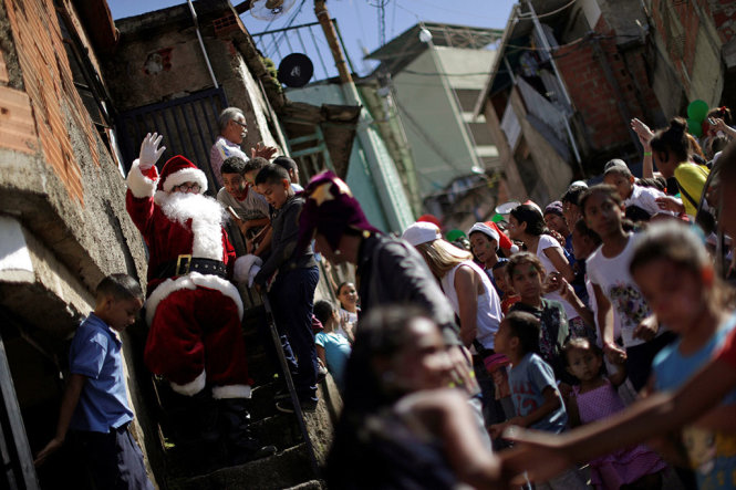 Các trẻ em tại khu ổ chuột Petare (Venezuela) bất ngờ với sự xuất hiện của “ông già Noel” - Ảnh: Reuters