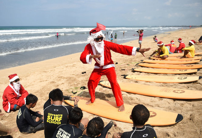 “Ông già Noel” nhiệt tình hướng dẫn kỹ thuật lướt ván cho trẻ em tại bãi biển đảo Bali (Indonesia) - Ảnh: AFP/Getty