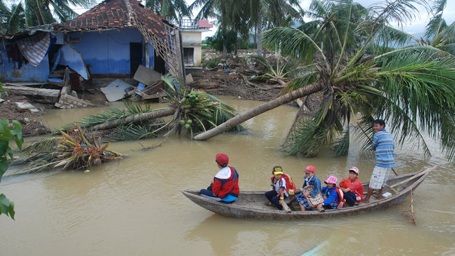 Hình ảnh đầy tương phản về ý chí không khuất phục của con người: Nhóm học sinh được người đàn ông dùng “sõng” chèo luồn qua lạch nước mới bị lũ xé qua làng, các em nhỏ trở lại lớp sau khi lũ đi qua - Ảnh: B.D