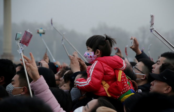 Người dân đeo khẩu trang xem thượng cờ ở Thiên An Môn, Bắc Kinh hôm 20-12 trong bầu không khí ô nhiễm - Ảnh: Reuters
