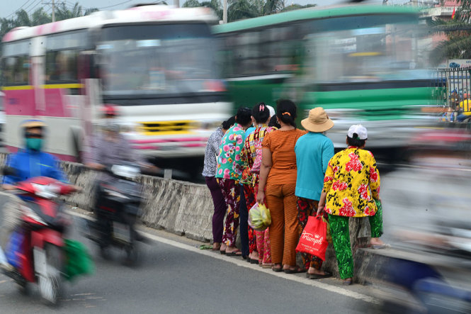 Một nhóm phụ nữ đứng chờ vượt dải phân cách để qua đường trên quốc lộ 1 đoạn qua Q.Bình Tân, TP.HCM chiều 4-1 - Ảnh: QUANG ĐỊNH