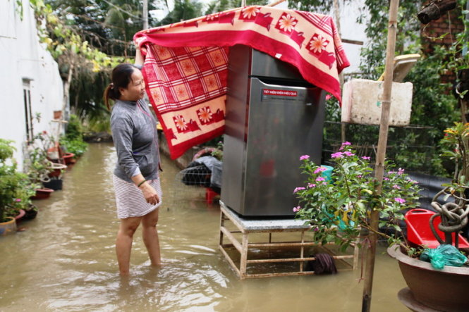 Người dân khiêng tủ lạnh lên cao để tránh nước - Ảnh: Lê Phan
