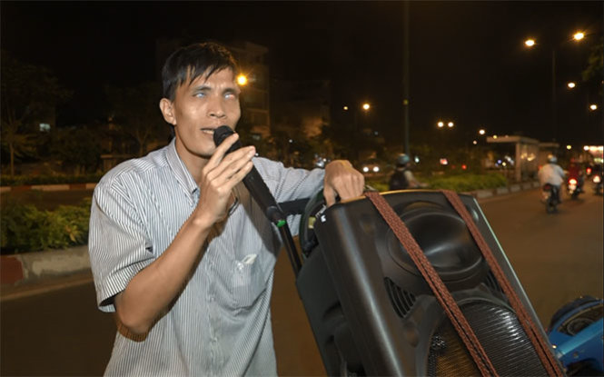 Nghệ sĩ đường phố Trần Văn Hoàng quê Nha Trang, là một nghệ sĩ khiếm thị  nhưng với niềm đam mê âm nhạc anh hát bán kẹo mưu sinh hằng đêm tại vỉa hè đường Phạm Văn Đồng  - Ảnh: CHẾ THÂN