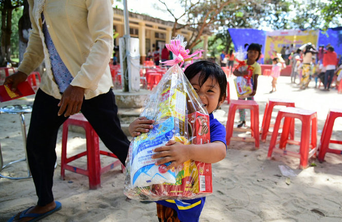 Cậu bé người Campuchia háo hức ôm phần quà - Ảnh: HỮU THUẬN