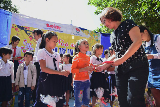 Bà Lê Thị Cúc (báo Tuổi Trẻ) trao quà cho các em học sinh - Ảnh: HỮU THUẬN